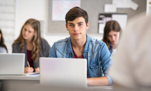 Estudante do ensino médio na sala de aula estudando com seu notebook.