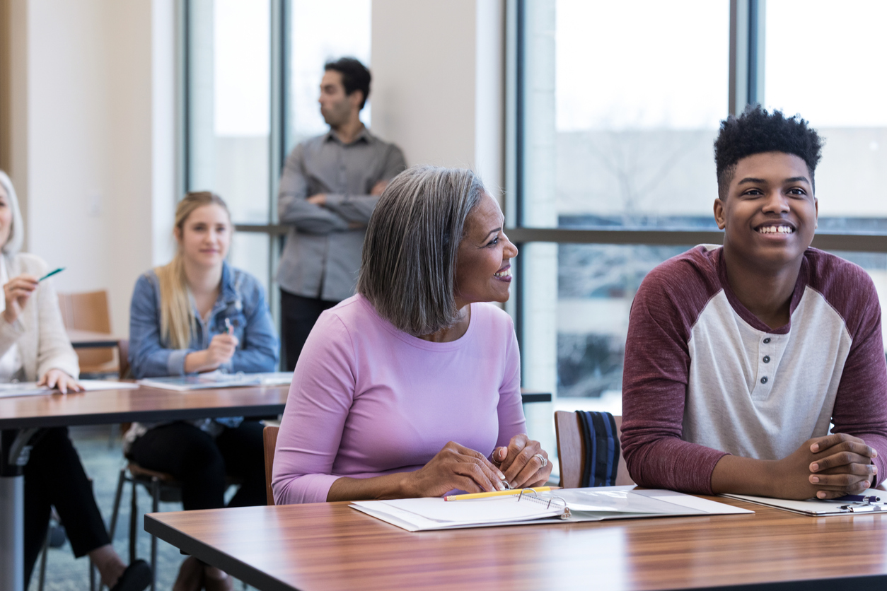 Pais e responsáveis com alunos durante reunião na escola.