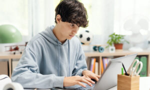 Aluno estudando em casa com o laptop.