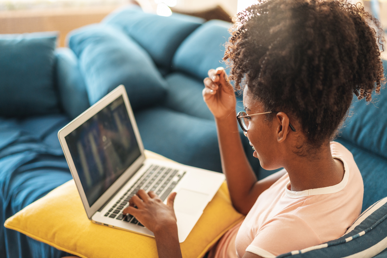 Aluna do ensino médio estudando de casa com notebook.