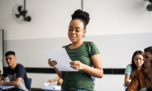 Estudante lendo atividade em voz alta na sala de aula.