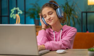Menina pré-adolescente com fone de ouvido assistindo aula, ensino on-line à distância.