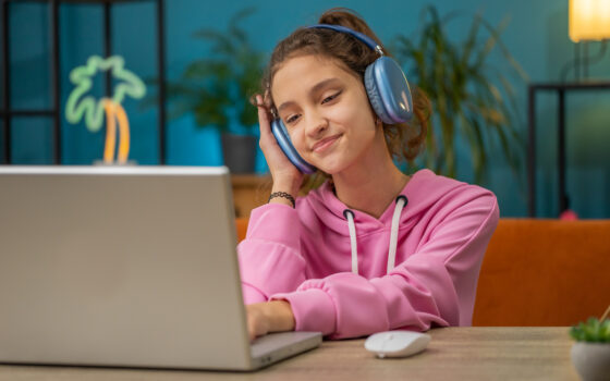 Menina pré-adolescente com fone de ouvido assistindo aula, ensino on-line à distância.