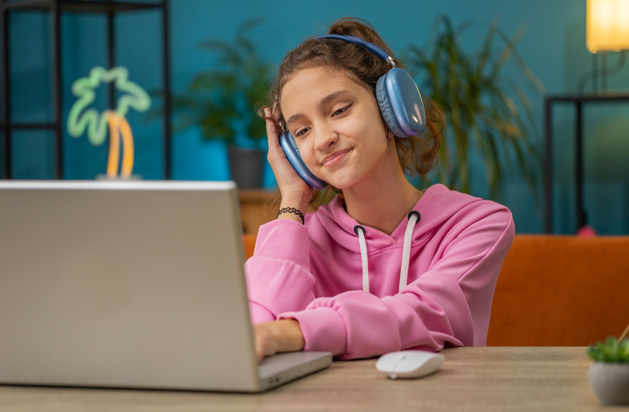 Menina pré-adolescente com fone de ouvido assistindo aula, ensino on-line à distância.